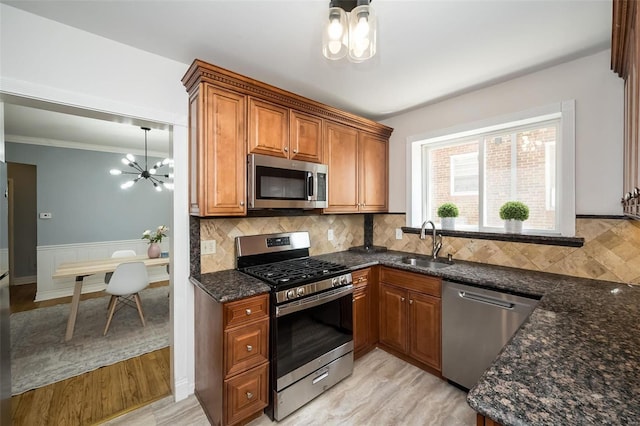 kitchen featuring sink, an inviting chandelier, backsplash, stainless steel appliances, and dark stone counters