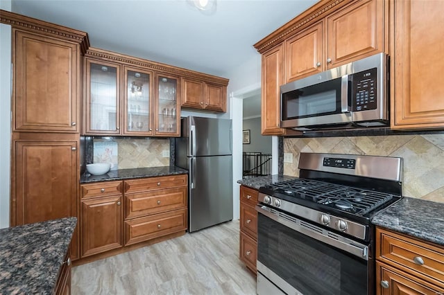 kitchen featuring appliances with stainless steel finishes, dark stone counters, and backsplash