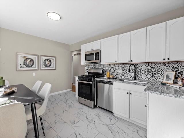 kitchen featuring stainless steel appliances, light stone countertops, sink, and white cabinets