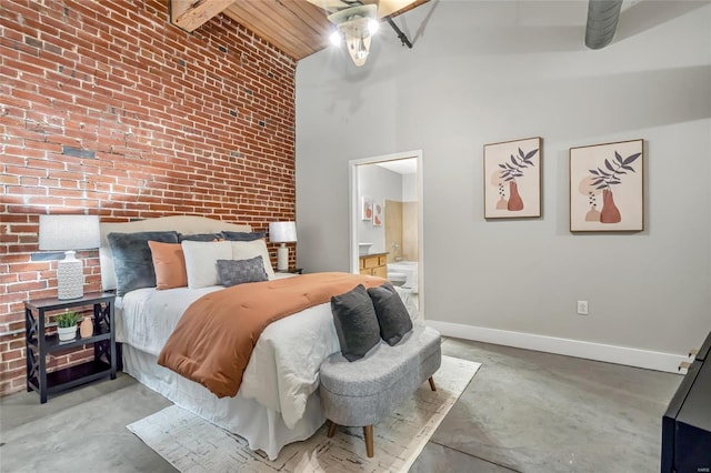 bedroom with a towering ceiling, connected bathroom, brick wall, concrete floors, and beamed ceiling