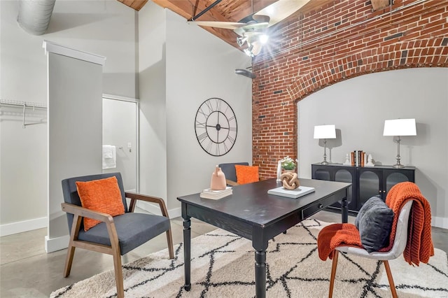 office space with concrete floors, a high ceiling, and brick wall