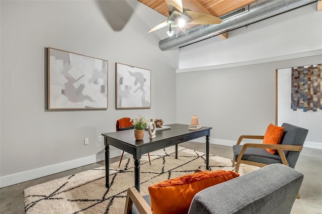 office area featuring concrete floors, ceiling fan, and a high ceiling