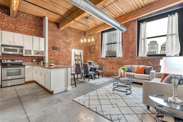 kitchen with wood ceiling, stainless steel appliances, white cabinets, and brick wall