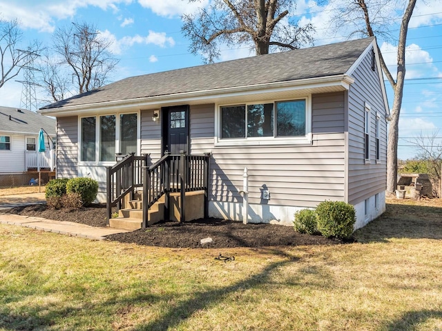 view of front of property with a shingled roof and a front lawn