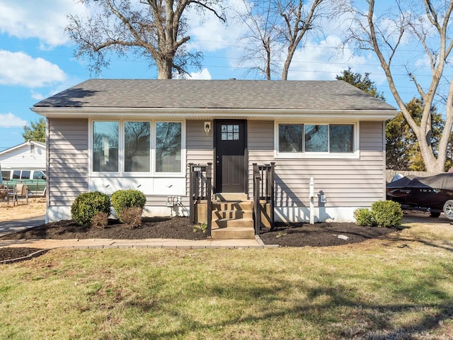 bungalow-style house with a shingled roof and a front lawn