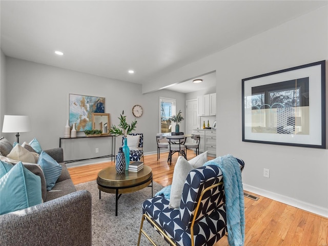 living area with light wood-type flooring, visible vents, baseboards, and recessed lighting