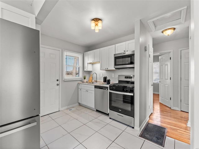 kitchen with baseboards, white cabinetry, stainless steel appliances, and a sink