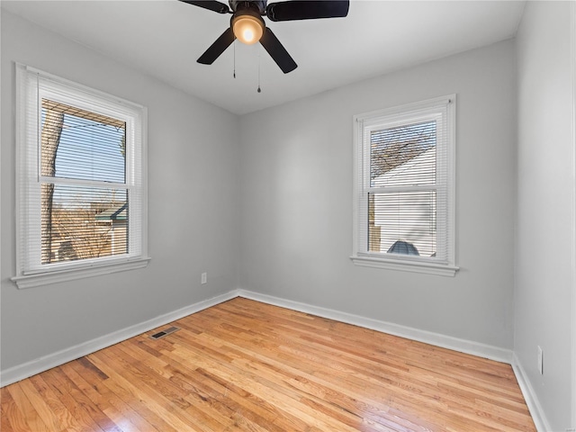 unfurnished room with light wood-style floors, visible vents, ceiling fan, and baseboards