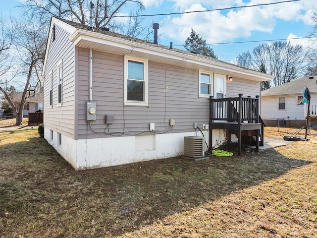 rear view of property with central AC and a lawn