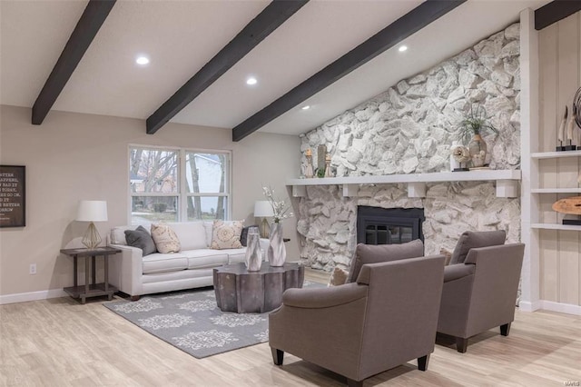 living room with light wood-type flooring, beamed ceiling, and a stone fireplace