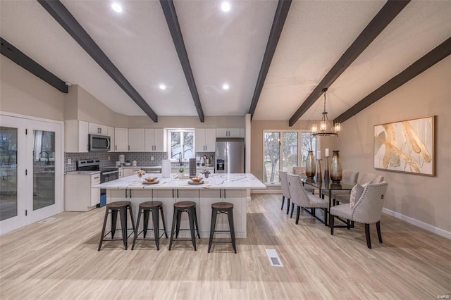 kitchen featuring white cabinetry, a large island, appliances with stainless steel finishes, backsplash, and vaulted ceiling with beams