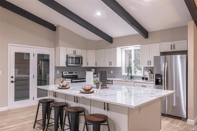 kitchen with white cabinets, stainless steel appliances, a breakfast bar area, and a kitchen island