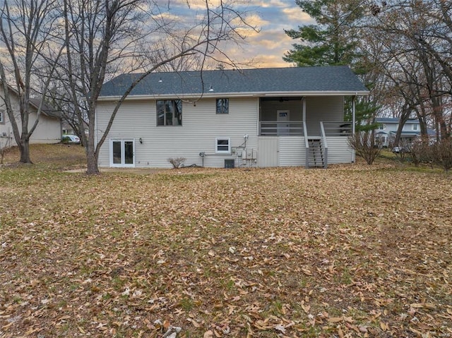 back house at dusk with a lawn