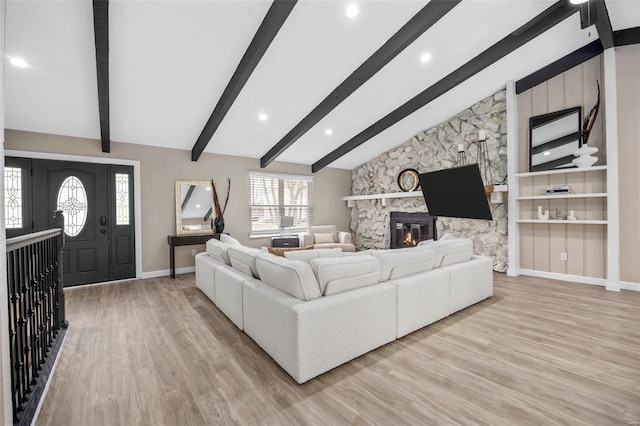 living area featuring lofted ceiling with beams, a fireplace, light wood-type flooring, and baseboards