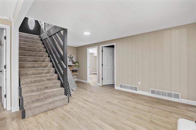 stairway with wood finished floors, visible vents, and baseboards