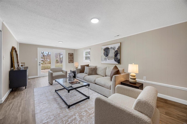 living room with a textured ceiling, baseboards, and wood finished floors