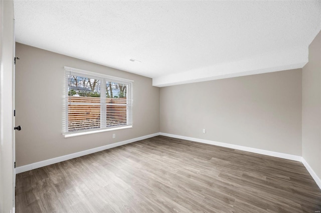 empty room featuring baseboards, a textured ceiling, and wood finished floors