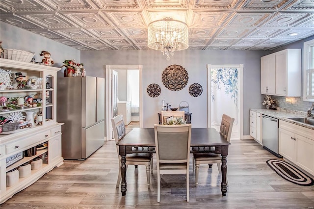 dining space featuring sink, light hardwood / wood-style flooring, and a chandelier