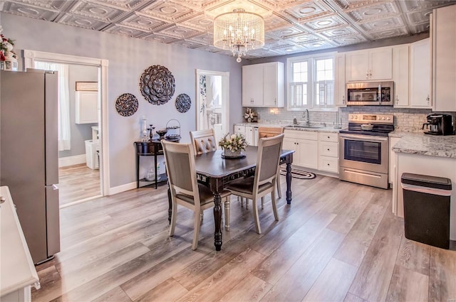 dining space featuring sink, light hardwood / wood-style floors, and a chandelier