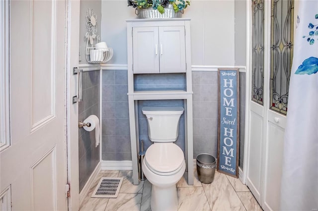 bathroom featuring toilet and tile walls