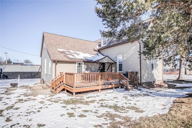 snow covered back of property with a deck