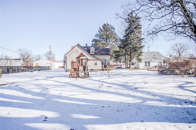 snow covered back of property with a playground