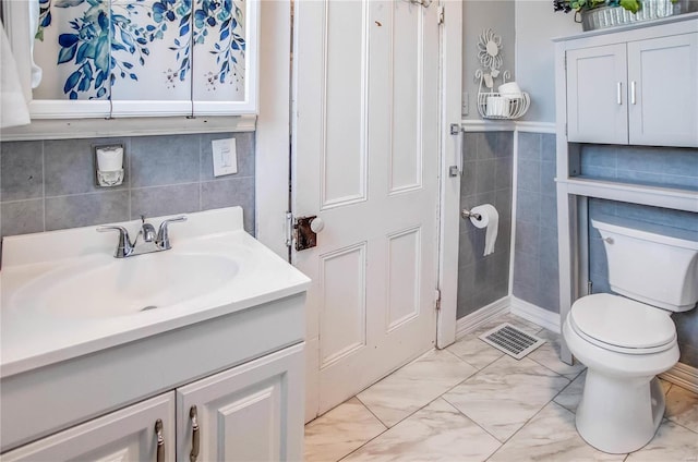 bathroom featuring vanity, toilet, and tile walls