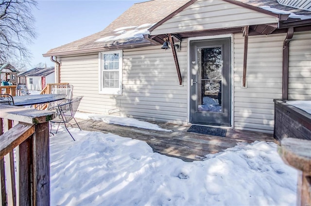 snow covered property entrance with a wooden deck