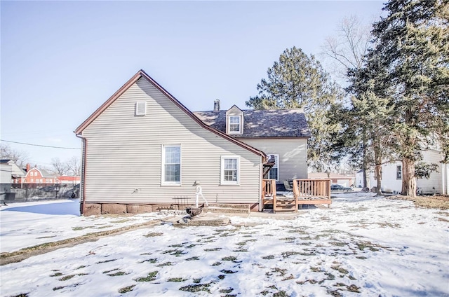 snow covered back of property with a wooden deck