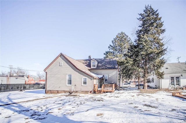 snow covered back of property with a wooden deck