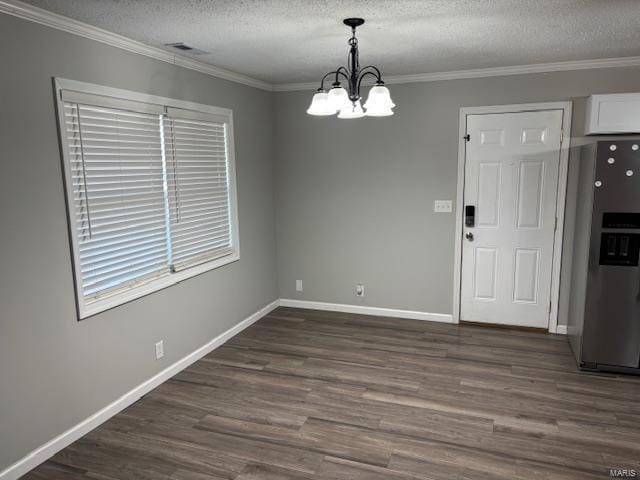 unfurnished dining area with a textured ceiling, dark hardwood / wood-style flooring, crown molding, and an inviting chandelier