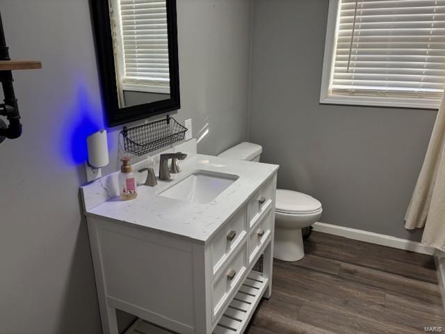 bathroom with toilet, vanity, and wood-type flooring