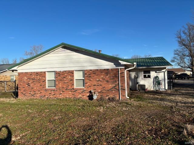 view of side of property featuring cooling unit and a lawn