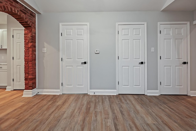 unfurnished bedroom featuring vaulted ceiling, light hardwood / wood-style floors, and two closets