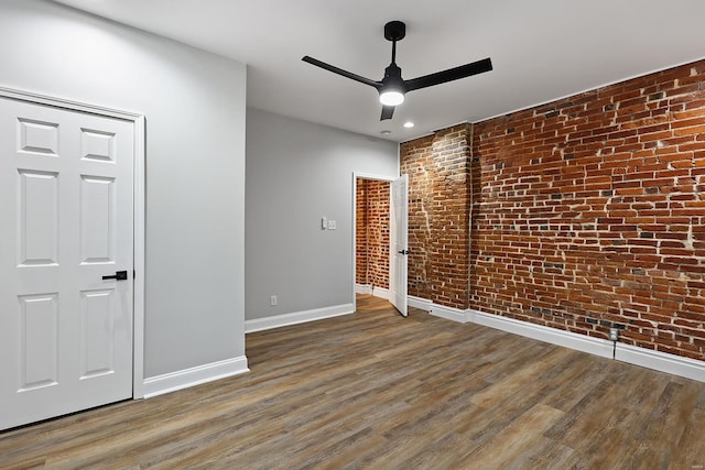 empty room with brick wall, hardwood / wood-style floors, and ceiling fan