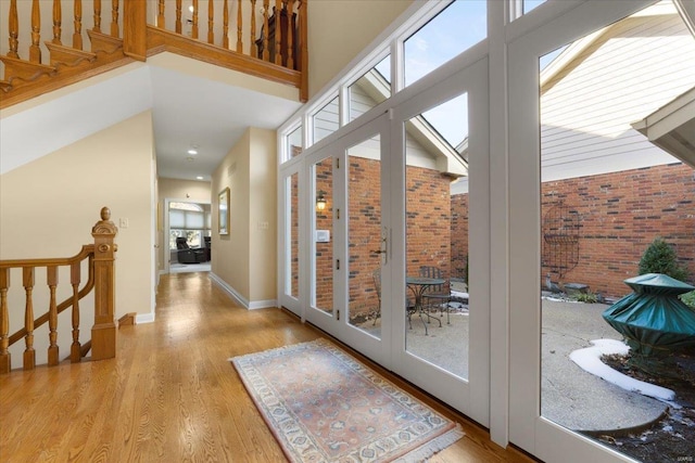 doorway with a towering ceiling and light wood-type flooring