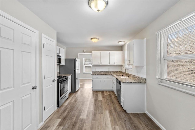 kitchen with sink, stone counters, white cabinetry, plenty of natural light, and stainless steel appliances