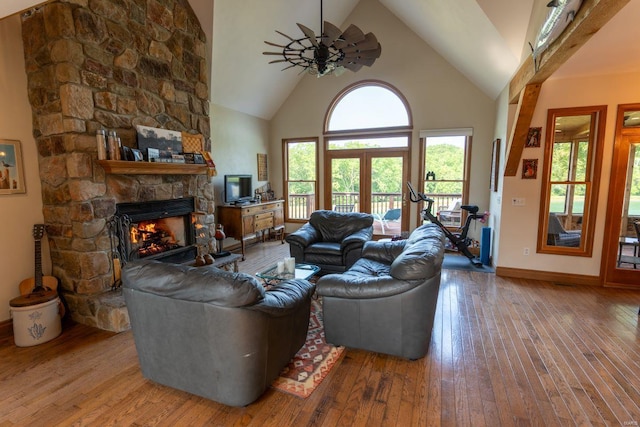 living room featuring ceiling fan, a fireplace, hardwood / wood-style floors, high vaulted ceiling, and french doors