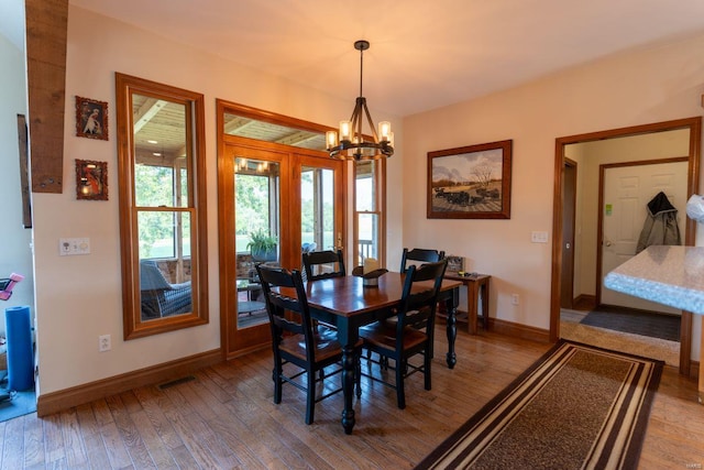 dining area with hardwood / wood-style floors and a notable chandelier