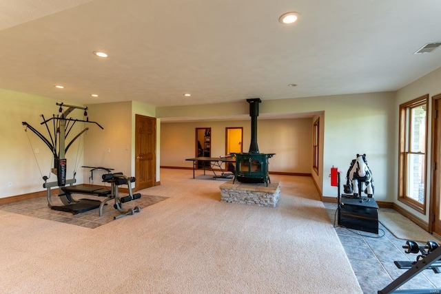 exercise area with a wood stove and light carpet