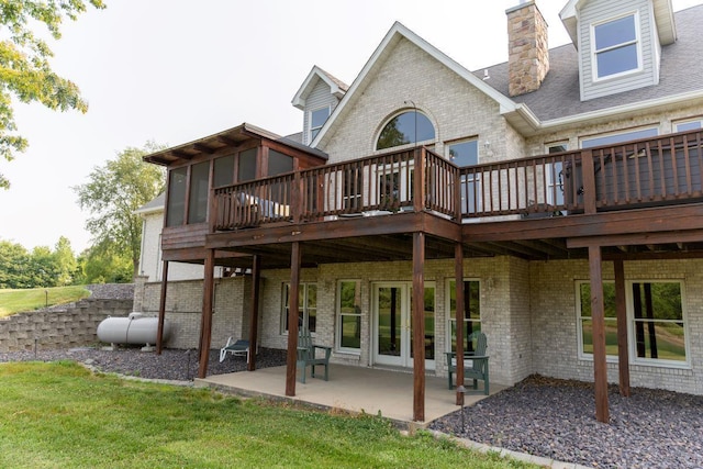 rear view of property featuring a deck, a patio area, a sunroom, and a yard