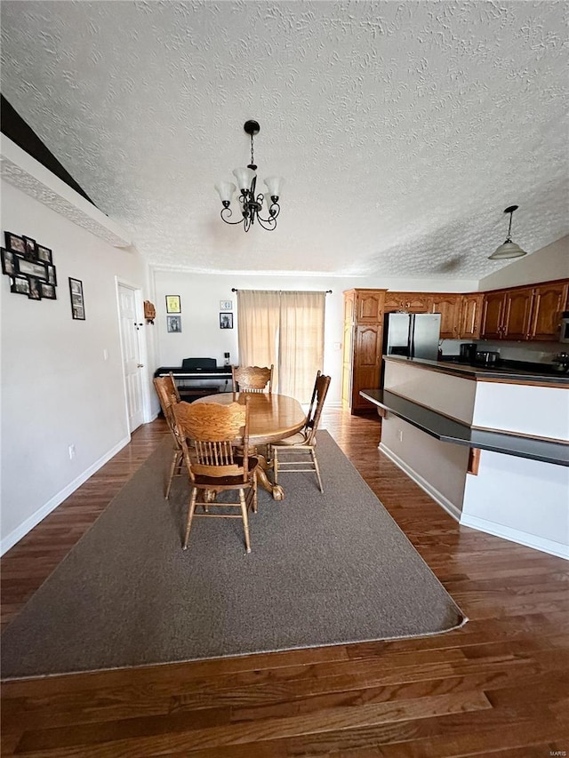 dining room featuring an inviting chandelier, a textured ceiling, dark hardwood / wood-style floors, and lofted ceiling