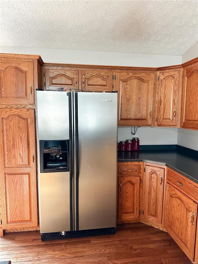 kitchen with dark hardwood / wood-style floors, a textured ceiling, and stainless steel fridge