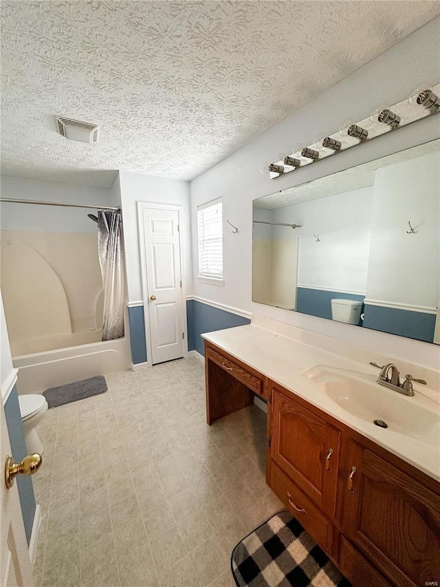 full bathroom with vanity, toilet, shower / bath combo, and a textured ceiling