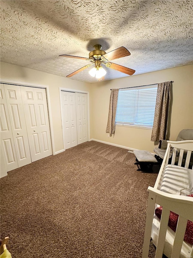 unfurnished bedroom featuring ceiling fan, two closets, carpet, and a textured ceiling