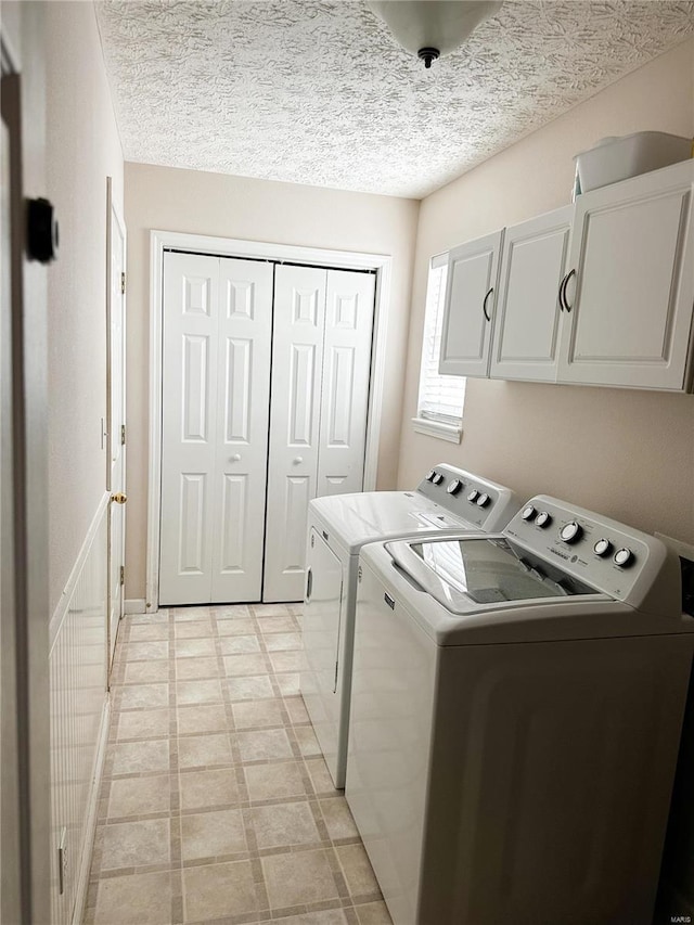 laundry room featuring cabinets, a textured ceiling, and washer and dryer