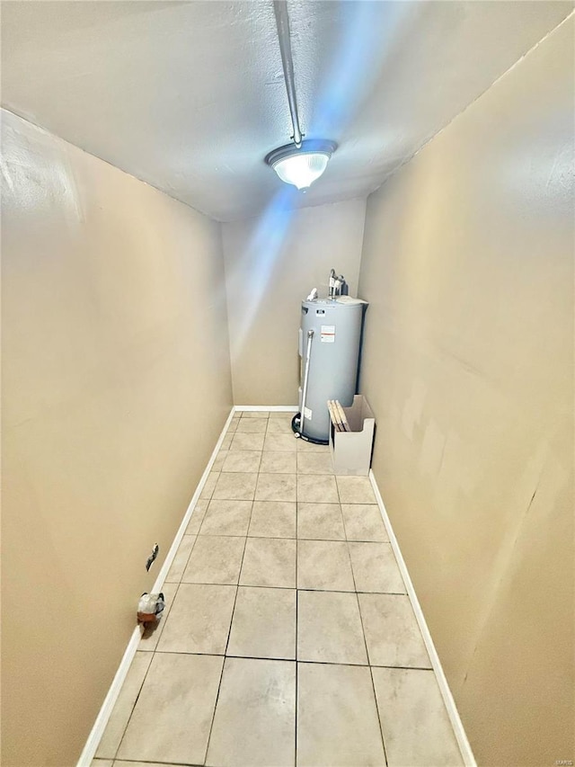 corridor with light tile patterned floors, water heater, and a textured ceiling