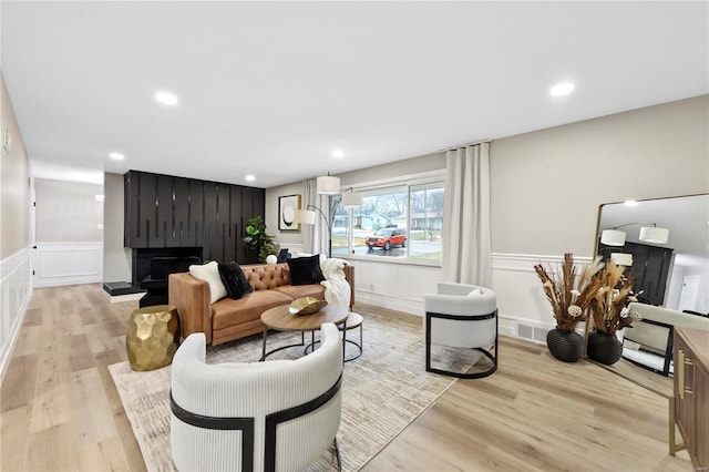 living room featuring light hardwood / wood-style flooring and a large fireplace