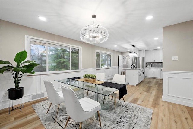 dining space featuring a notable chandelier and light wood-type flooring