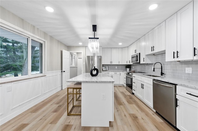 kitchen with light stone countertops, appliances with stainless steel finishes, a center island, and pendant lighting